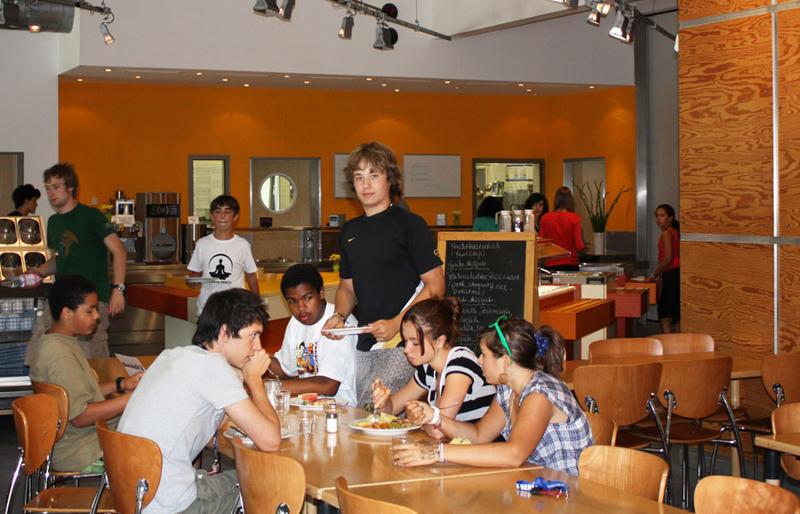 Grupo de jovens a almoçar juntos na cantina, desfrutando de uma pausa durante o seu curso de inglês na alemanha.