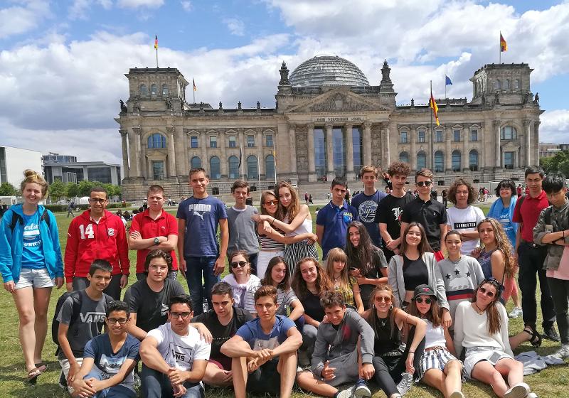 Grupo de participantes a posar em frente a locais históricos de Berlim num dia de sol, aproveitando a experiência cultural durante o seu curso de inglês na alemanha.
