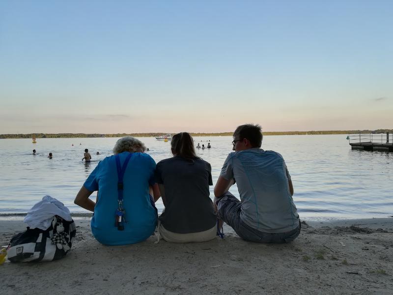 Três participantes a observar o pôr do sol no rio, relaxando após um dia de atividades no seu curso de inglês na alemanha.