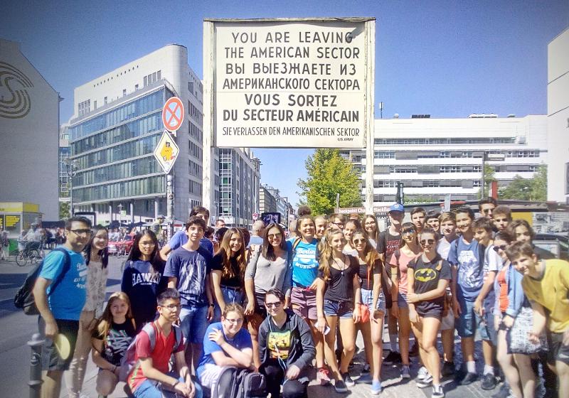 Participantes à frente do Checkpoint Charlie, explorando um local histórico durante o seu curso de inglês na alemanha.