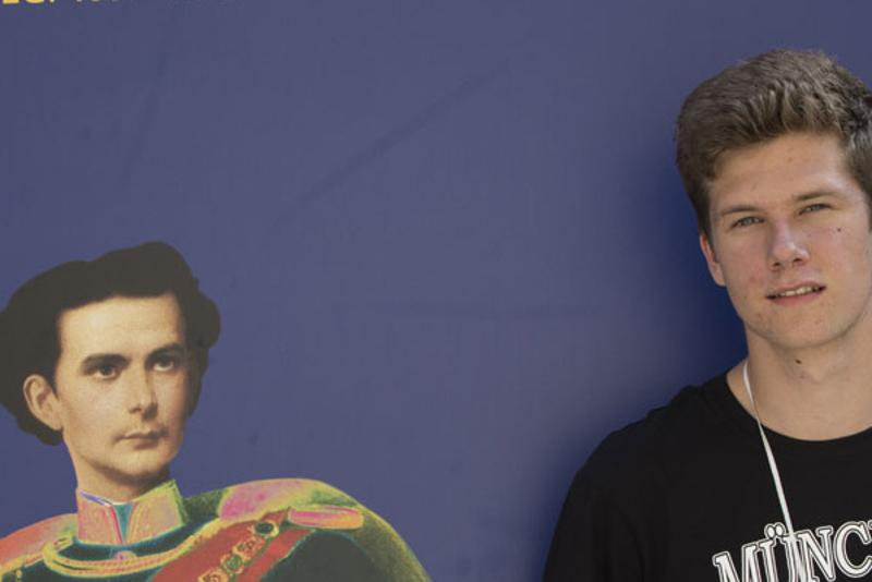 Participante ao lado de uma imagem de uma figura histórica, explorando a cultura e história durante o seu curso de inglês na alemanha.