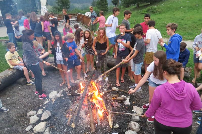 Grupo de participantes a reunir-se em torno de uma fogueira, aproveitando a noite ao ar livre durante o seu curso de inglês na alemanha.