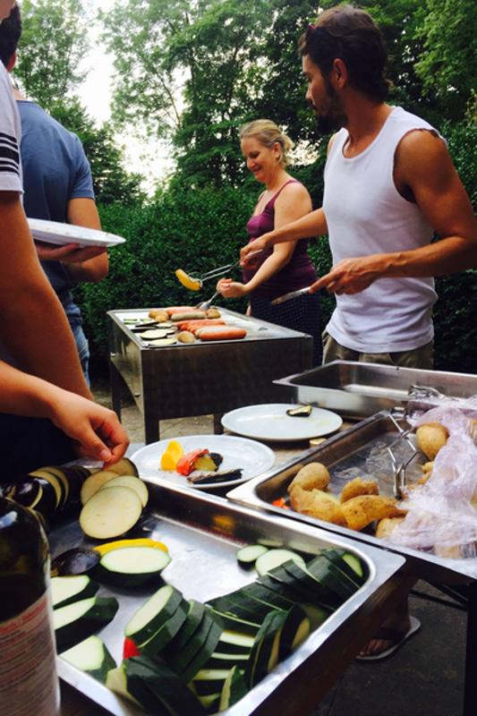 Grupo de participantes a saborear comida grelhada do barbecue, desfrutando de um momento de convívio durante o seu curso de inglês na alemanha.