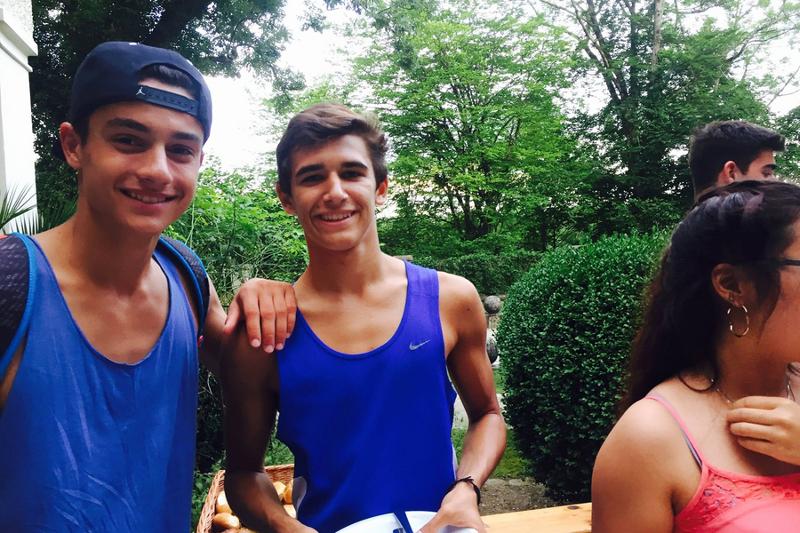 Dois rapazes a sorrir para a foto, vestidos com blusa azul, desfrutando do momento durante o seu curso de inglês na alemanha.
