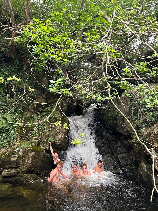 Jovens a relaxar junto a uma cascata, aproveitando a natureza enquanto fazem o seu curso de ingles na irlanda.