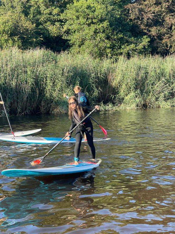 Criança a fazer paddle, divertindo-se nas águas enquanto faz o seu curso de ingles na irlanda.