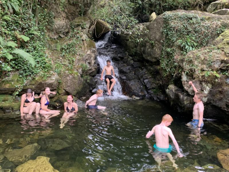 Jovens a explorar e a divertir-se perto de uma cascata, aproveitando a natureza enquanto fazem o seu curso de ingles na irlanda.