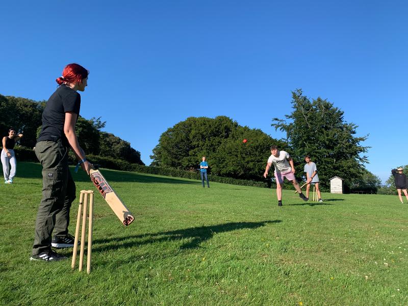 Jovens a jogar cricket no relvado, divertindo-se e praticando desporto enquanto fazem o seu curso de ingles na irlanda.