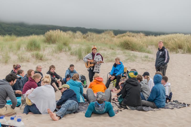 Grupo de jovens na areia da praia, enquanto fazem o seu curso de ingles na irlanda.