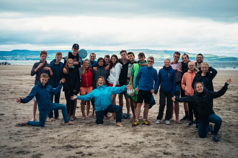 Grupo de jovens a relaxar na areia da praia, a aproveitar o ambiente e a diversão enquanto fazem o seu curso de ingles na irlanda.