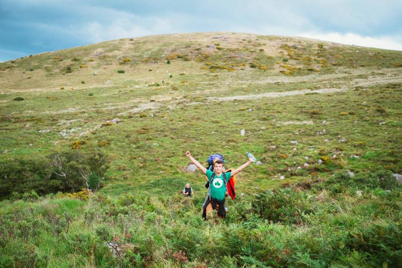 Rapaz feliz a fazer hiking, a explorar as montanhas enquanto faz o seu curso de ingles na irlanda.