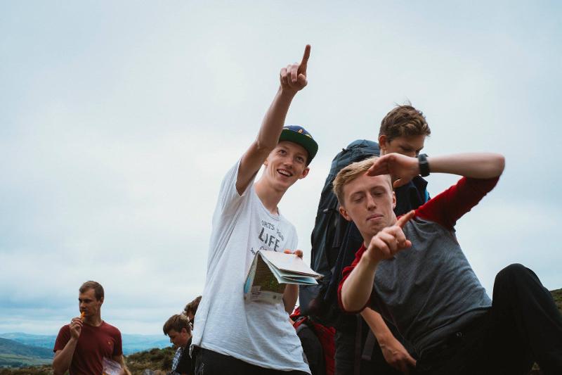 Jovens com o mapa na mão, a apontar para a frente enquanto exploram as montanhas durante o seu curso de ingles na irlanda.