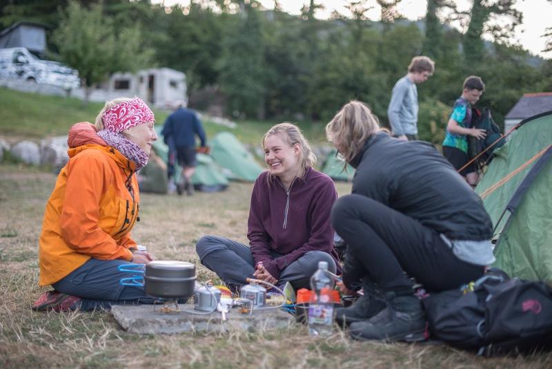 Jovens a sorrir à frente das tendas, sentados a comer e a desfrutar da companhia enquanto fazem o seu curso de ingles na irlanda.