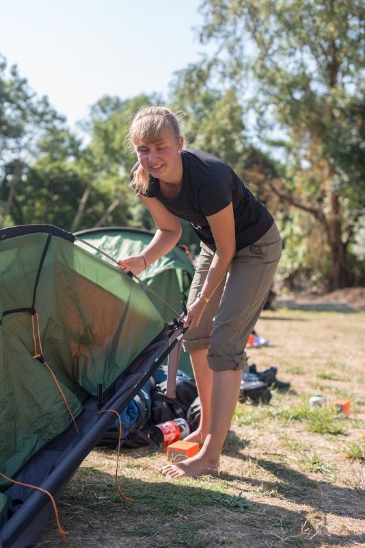 Menina a sorrir enquanto entra na sua tenda verde, enquanto faz o seu curso de ingles na irlanda.