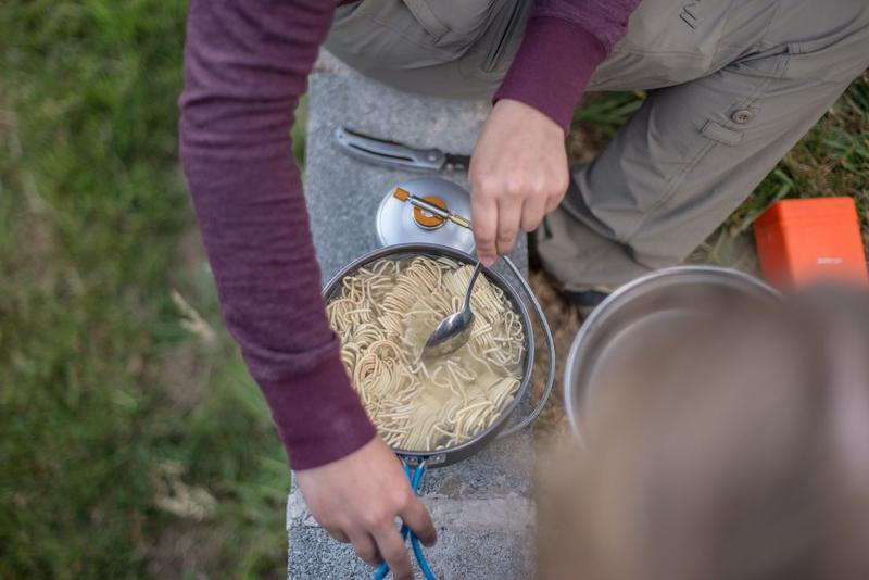 Jovem a cozinhar noodles ao ar livre, a preparar uma refeição simples enquanto faz o seu curso de ingles na irlanda.