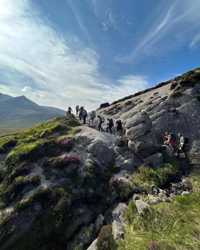 Jovens a caminhar em fila indiana na montanha, a explorar a natureza enquanto fazem o seu curso de ingles na irlanda.