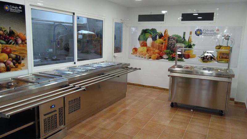 Refeitório moderno com balcão de inox e decoração colorida de frutas e vegetais, proporcionando refeições em ambientes de estudo, como num curso de lingua espanhola.