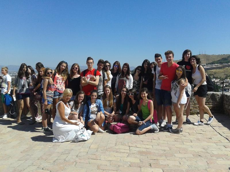 Grupo de estudantes a posar juntos ao ar livre sob um céu limpo, celebrando experiências culturais durante um curso de lingua espanhola.