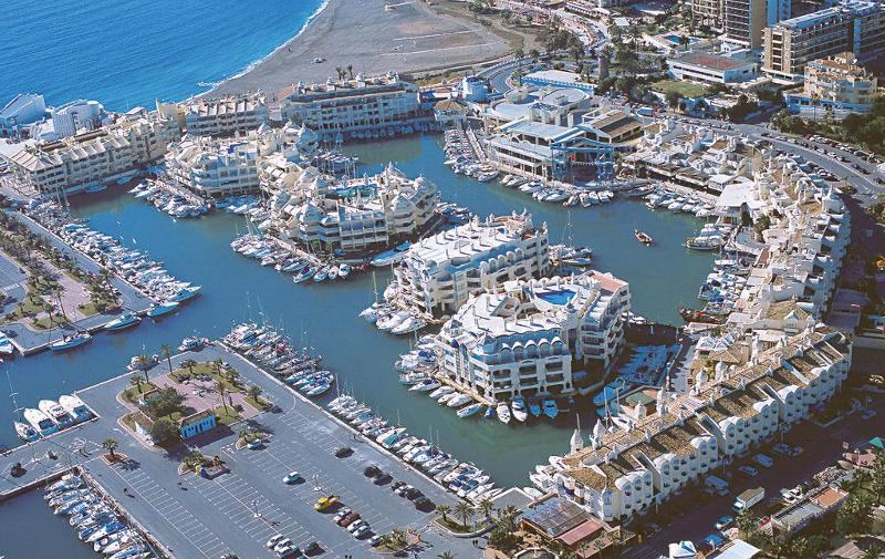 Vista aérea de uma marina com complexos residenciais e barcos, oferecendo um cenário vibrante para um curso de lingua espanhola.