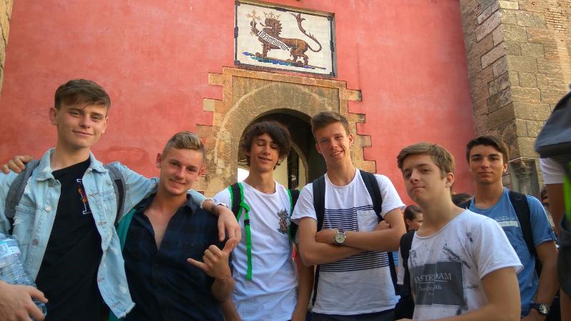 Grupo de jovens a sorrir diante de uma fachada histórica decorada, aproveitando o ambiente cultural de um curso de lingua espanhola.