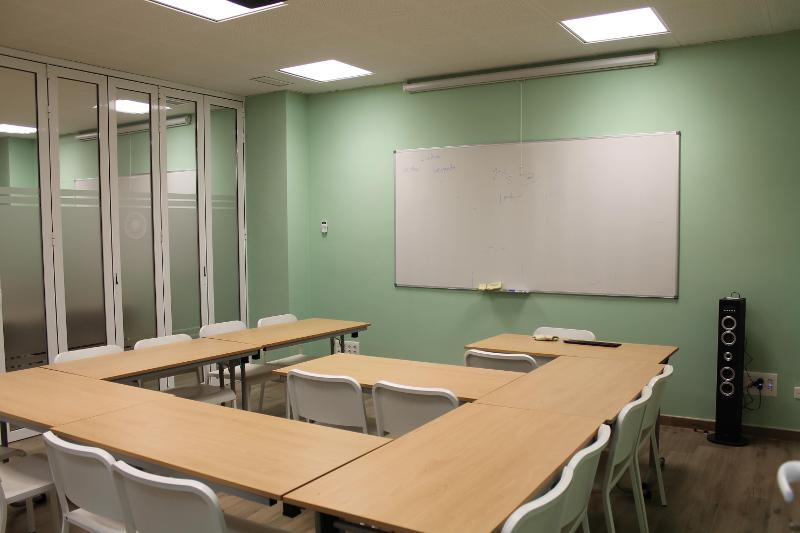 Sala de aula moderna e organizada com disposição em formato U, ideal para interação durante um curso de lingua espanhola.