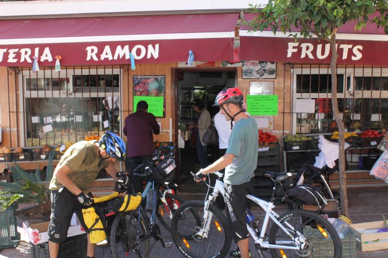 Ciclistas parados em frente a uma frutaria típica, aproveitando uma pausa durante um passeio cultural num curso de lingua espanhola.