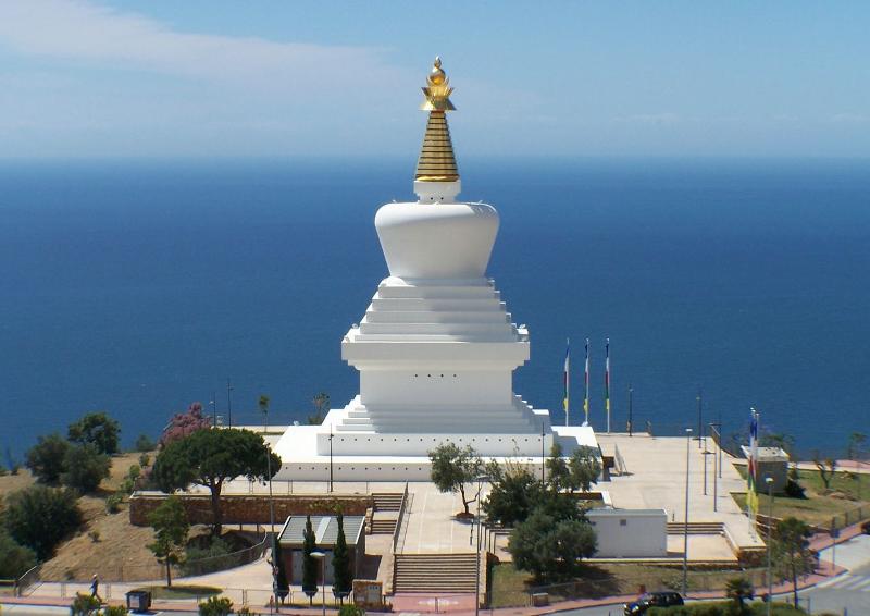 Estupa branca com cúpula dourada em destaque, situada com vista para o mar, um ponto sereno para um curso de lingua espanhola.