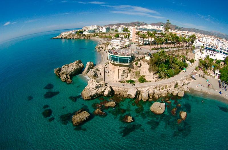 Vista aérea de uma costa com águas cristalinas e uma estrutura em penhasco, criando um cenário vibrante para um curso de lingua espanhola.