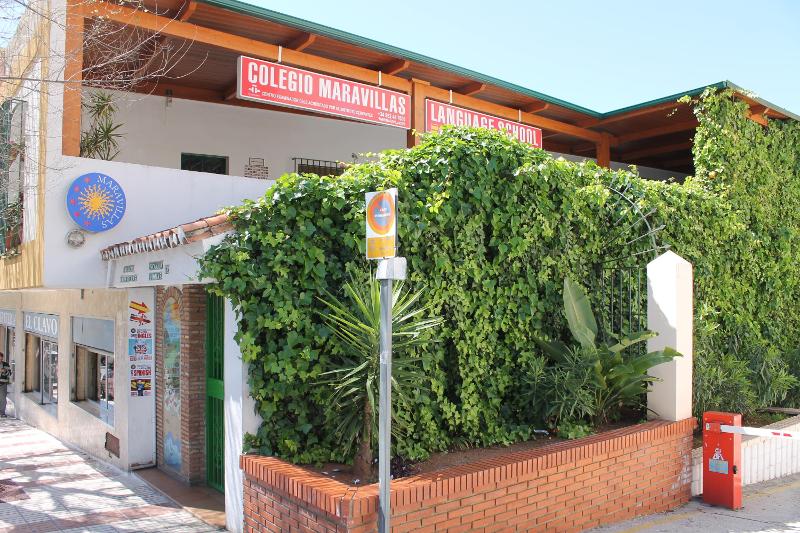 Fachada de uma escola de línguas rodeada por plantas verdes, ideal para experiências imersivas num curso de lingua espanhola.