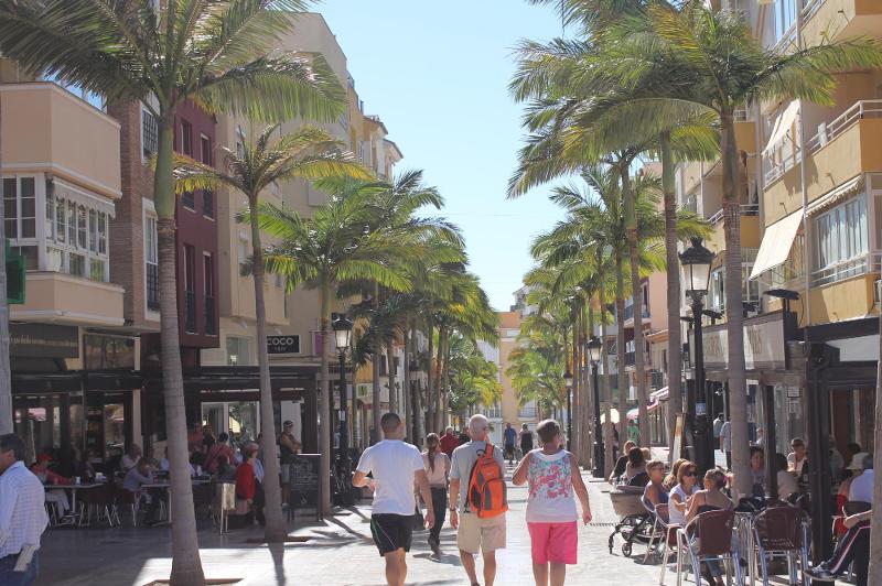 Rua pedonal com palmeiras e pessoas a passear e desfrutar de cafés ao ar livre, criando uma atmosfera vibrante para um curso de lingua espanhola.