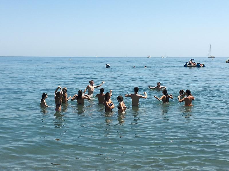 Grupo de pessoas a jogar voleibol na água do mar, aproveitando atividades ao ar livre durante um curso de lingua espanhola.