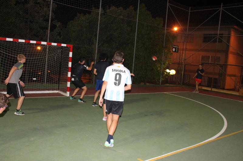 Jovens a jogar futebol à noite num campo desportivo ao ar livre, aproveitando atividades físicas durante um curso de lingua espanhola.
