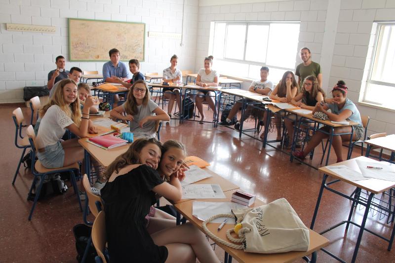 Grupo de estudantes sorridentes na sala de aula durante um curso de espanhol, aproveitando o aprendizado e a convivência.