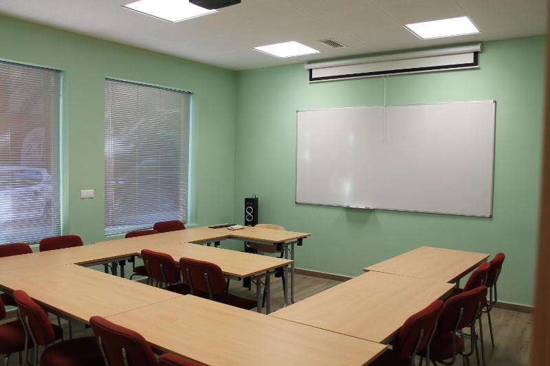 Sala de aula moderna e bem iluminada, pronta para o seu curso de espanhol, com mesas organizadas e uma lousa branca.