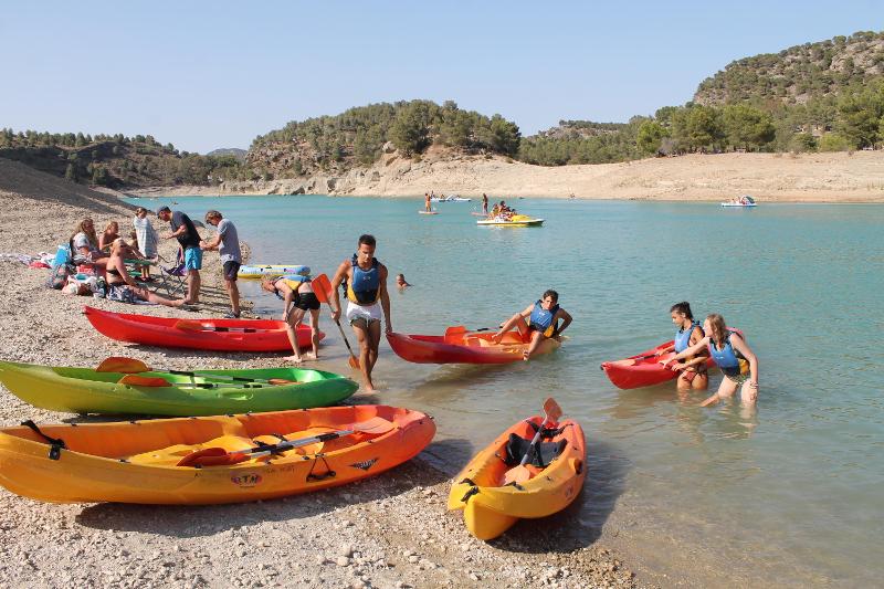 Estudantes a desfrutar de uma atividade de caiaque no curso de espanhol, aproveitando o lago e o sol.