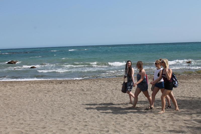 Estudantes a caminhar na praia durante o seu tempo livre no curso de espanhol, desfrutando do sol e da vista.
