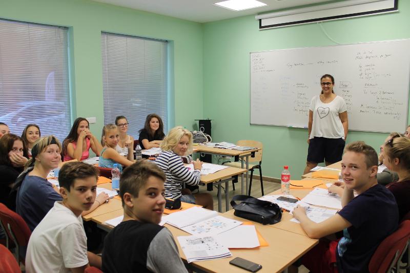 Alunos participando ativamente numa aula de espanhol, com a professora à frente, num ambiente animado e interativo dos cursos de linguas em espanha.