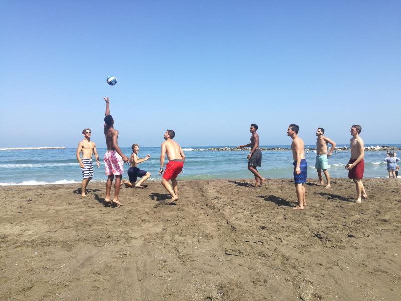 Grupo de jovens a jogar voleibol de praia, aproveitando o sol e a areia enquanto desfrutam de uma pausa durante os cursos de linguas em espanha.