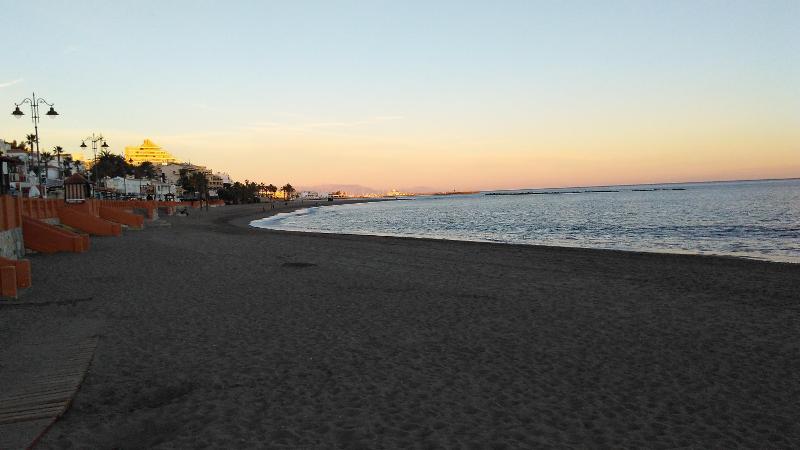 Imagem de uma praia tranquila ao pôr-do-sol, um cenário perfeito para relaxar depois dos cursos de linguas em espanha.