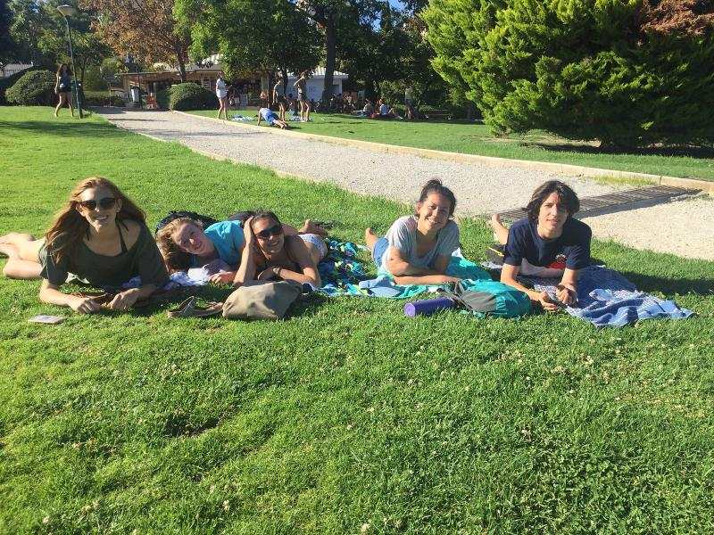 Grupo de estudantes deitados na relva, a desfrutar de momentos de lazer após os cursos de linguas em espanha.
