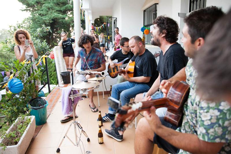 Jovens sentados a tocar vários instrumentos musicais durante o curso de línguas