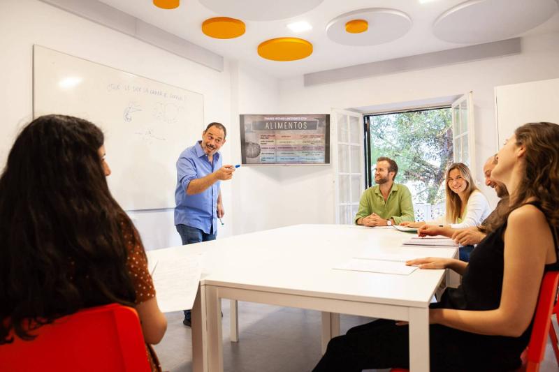 Professor a dar aula a seis alunos de forma divertida durante os cursos de línguas em espanha