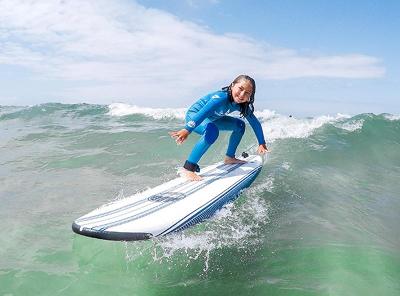 Menina a sorrir enquanto está a surfar durante o surfcamp lisbon