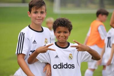 dois participantes rapazes a usarem o equipamento de futebol do Real Madrid no campo de ferias